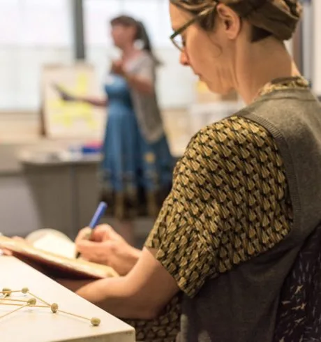 A woman is sitting at a desk writing in a notebook