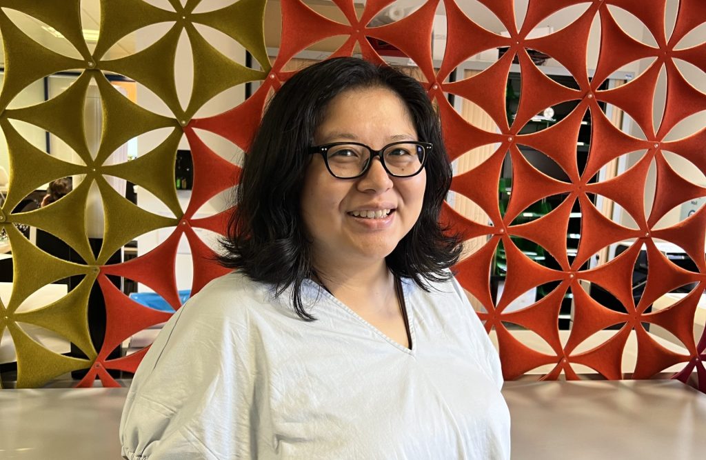 Tonia Lu, wearing a grey shirt and glasses. Brown hair.
