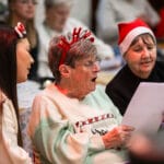 Three women in festive dress sitting and singing