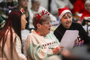 Three women in festive dress sitting and singing