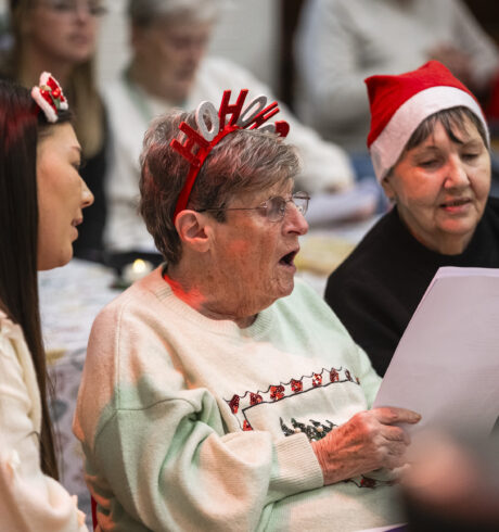 Three women in festive dress sitting and singing
