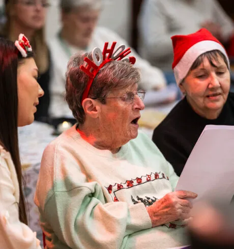 Three women in festive dress sitting and singing