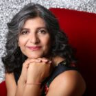 Photo of Arti Prashar sitting on a red chair