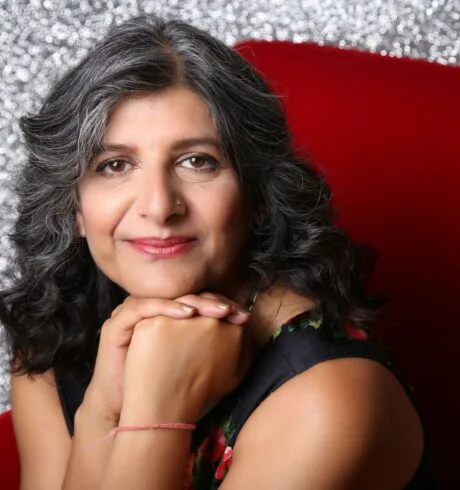 Photo of Arti Prashar sitting on a red chair
