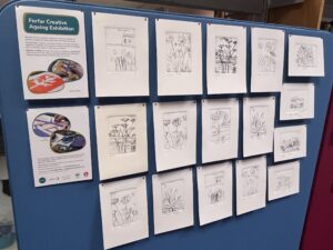 A selection of drawings pinned to a blue board.