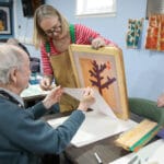 Screenprint being created by an older man with help from an artist