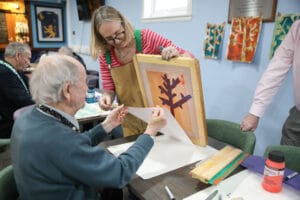 Screenprint being created by an older man with help from an artist