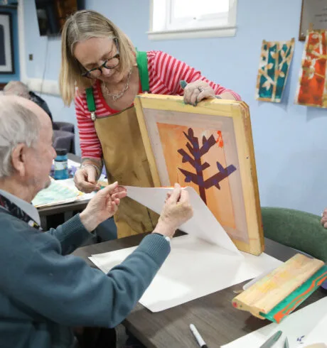 Screenprint being created by an older man with help from an artist