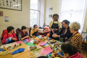 Art activities session with participants round a table covered in materials