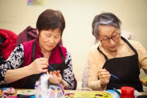 Two women at a table doing craft activities