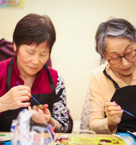 Two women at a table doing craft activities