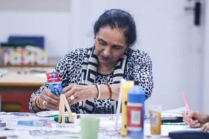 A woman at a table doing art activities squeezing paint out of a tube