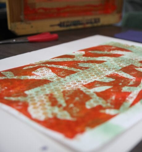 An orange and white abstract screenprint on a table.