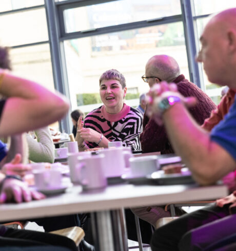A group of people chatting with coffees at a table.